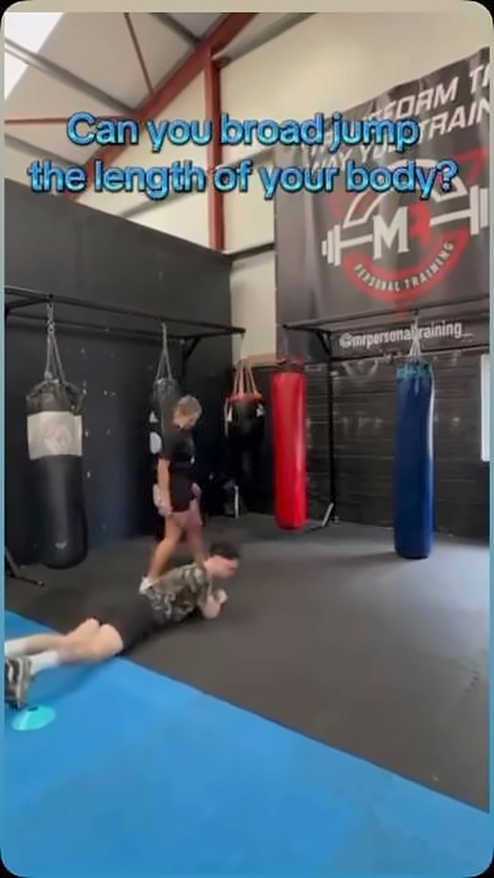 Two athletes doing a broad jump drill in front of the heavy bags